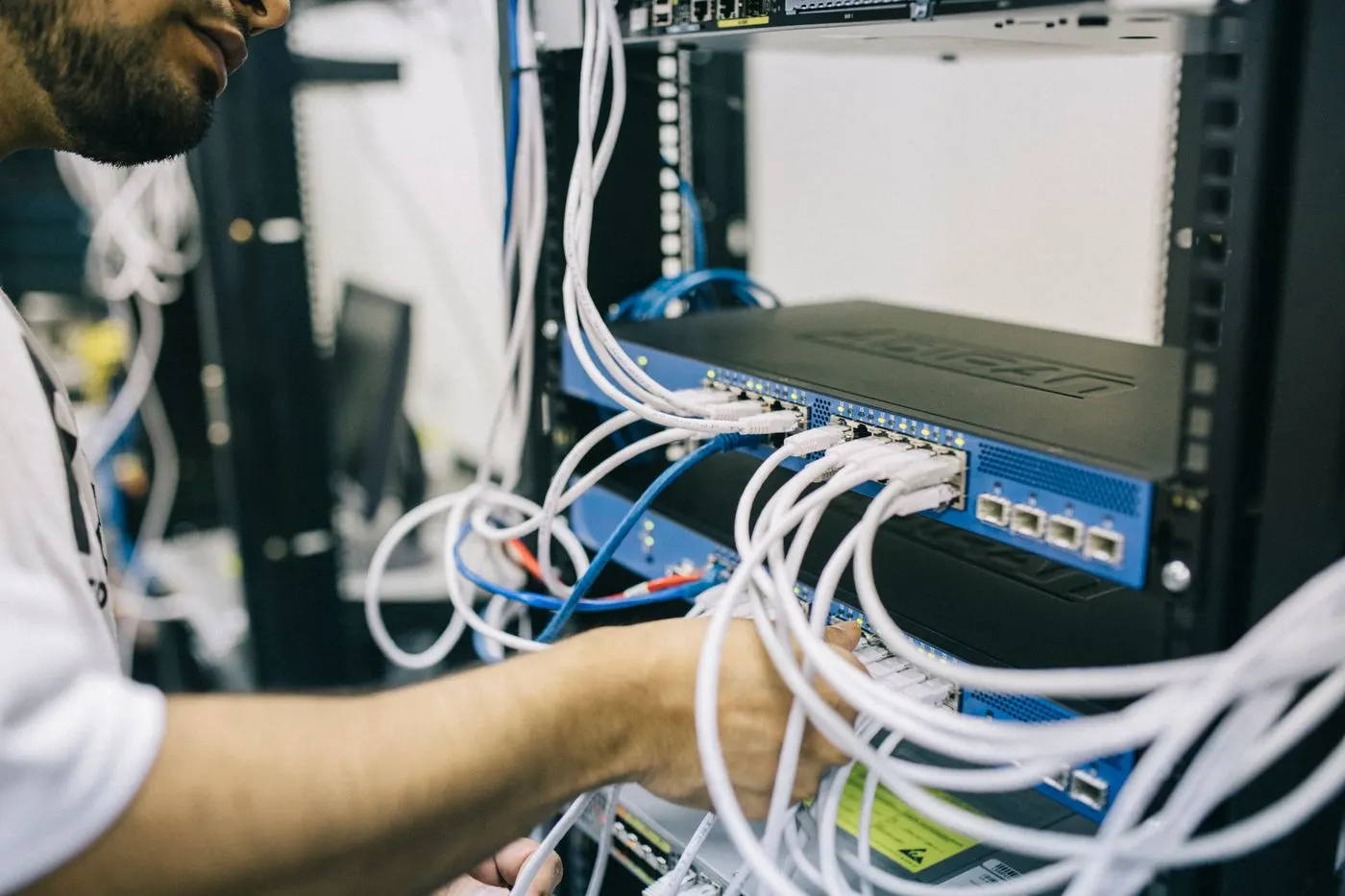 Network engineer plugging cables into a rack switch