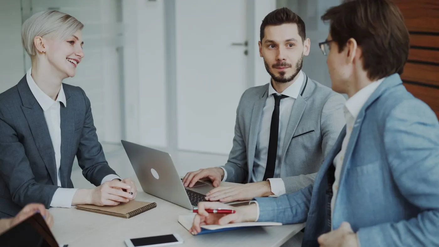 Trois professionnels en réunion autour d'un ordinateur portable